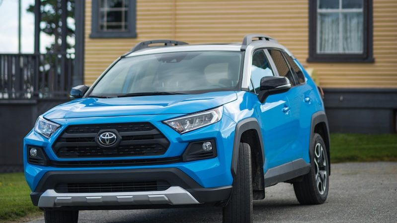 a blue toyota rav parked in front of a house